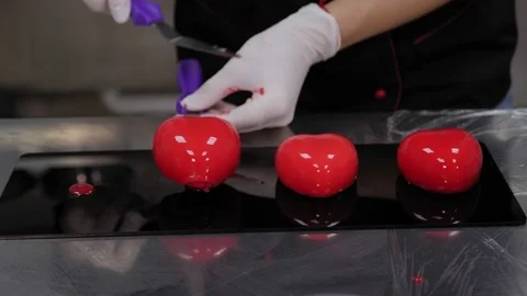 Close-up of a pastry chef preparing mousse cakes with mirrored red icing. Stock Footage 136845773