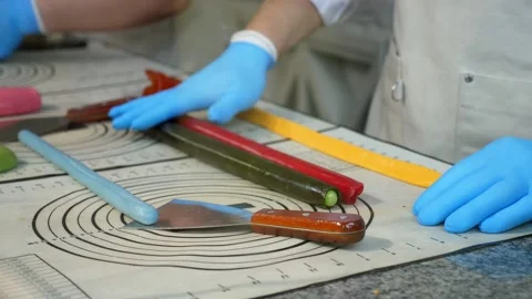 Close-up of a pastry chef rolling out soft caramel on a table in a pastry shop. Stock Footage 330522445