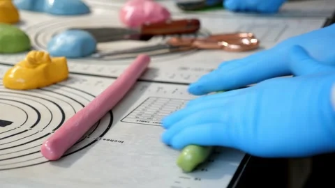 Close-up of a pastry chef rolling out soft caramel on a table in a pastry shop. Stock Footage 332411083