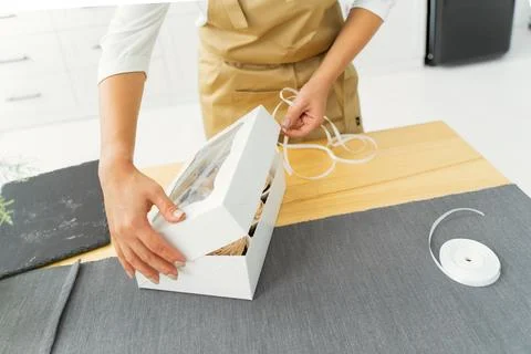 Close-up of a pastry chef in a white kitchen in a beige apron is packing Foto stock