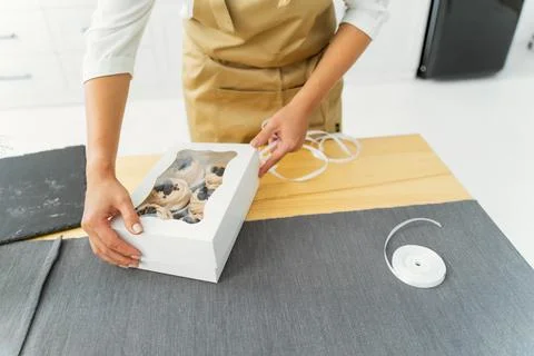 Close-up of a pastry chef in a white kitchen is packing a box of sweets Stock Photos