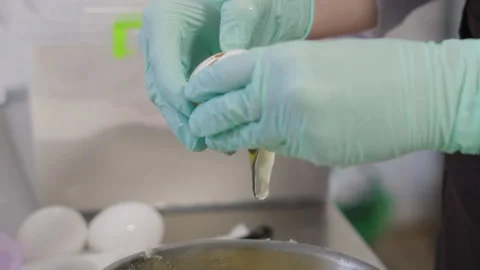 Close-up, Pastry Hands in Gloves Break Egg into Metal Pot with Cake Cream Stock Footage 136856284