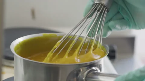 Close-up, Pastry Hands in Gloves Stir With a Whisk Cream Boiling on the Plate Stock Footage 136882091