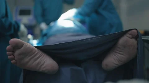 Close up of patient feet lying on operating bed in operating room at hospital Видео 234508860
