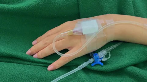 Close Up Patient Hand with Normal Saline IV Drip During Medical Treatment Care Stock Footage 328307183