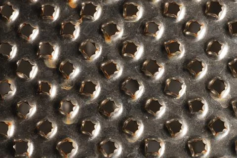 Close-up pattern of the holes of an old kitchen grater with rust elements Stock Photos
