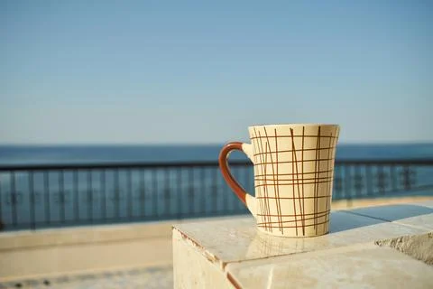 Close-up of a patterned ceramic coffee mug placed on a balcony overlooking .. Stock Photos