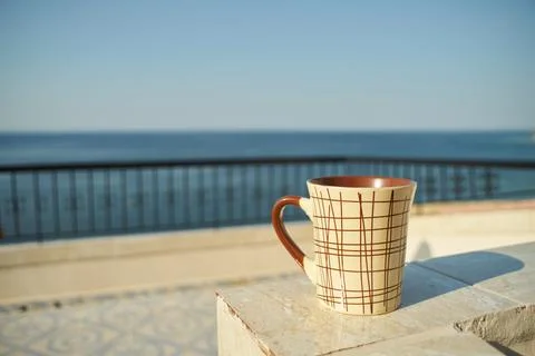 Close-up of a patterned ceramic coffee mug placed on a balcony overlooking .. Stock Photos