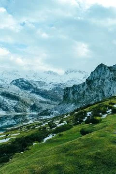 Close up of the peak of the mountain range with a vibrant green meadow Stock Photos