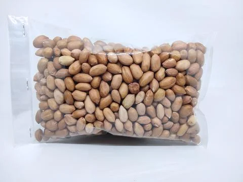 Close up of peanuts in plastic packaging ready for sale against white backgro 스톡 사진