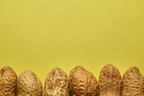Close-up of peanuts in shells against a yellow background. Stock Photos