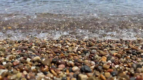 Close-up of pebble beach with transparent waves with sun glare on the water. Stock Footage 244380140