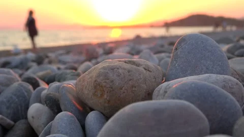 Close up pebbles and blurry shadow figures of people on the beach Stock Footage 137356472