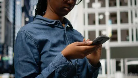 Close up of pedestrian typing text messages on her smartphone Stock Photos