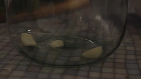 Close-up, Peeled Garlic Falls to the Bottom of a Glass Jar With Marinade Stock Footage 158260314