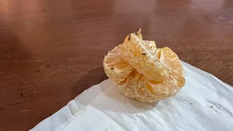 A close-up of a peeled orange segment resting on a white napkin Stock Photos