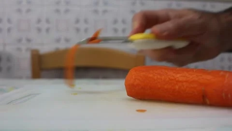 Close Up of Peeling Fresh Carrot with Vegetable Peeler on Cutting Board Stock Footage 340240271