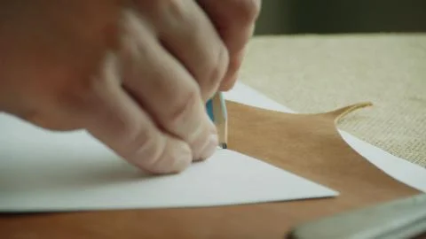 Close-up pencil outlines the pattern and marks a piece of genuine leather for Foto stock