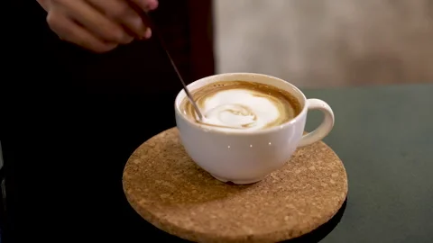 Close up people hands holding teaspoon in fresh cappuccino in white mug. li.. Stock Footage 245478019