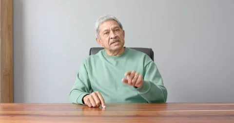 Close up of people talking to the camera, senior man in green sweater sitting at Stock Footage 345568776
