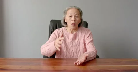 Close up of people talking to the camera, sitting at desk, elderly woman Stock Footage 345713336