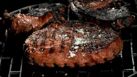 Close-up of the pepper falling on the delicious beef steak on the grill Stock Footage 281244263
