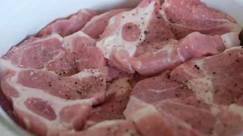 A close-up of peppered and salted raw pork slices in a cooking pot Stock Footage 282090564