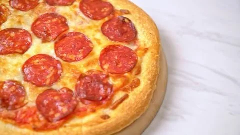 Close-up of pepperoni pizza slice with melted cheese on a white plate Stock Photos