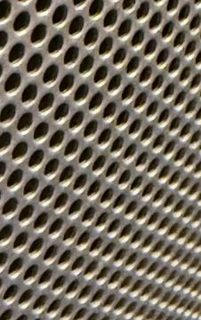 Close up of a perforated metal surface with repeating oval holes showing in.. 写真素材