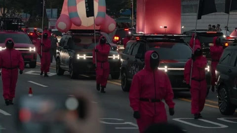 Close-up of performers in 'Squid Game' guard costumes marching in a Seoul Vidéo 312319922