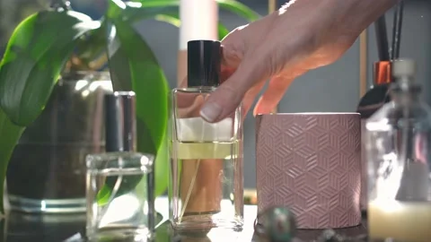 Close-up perfumes on table with slim female hand choosing cologne leaving in Video stock 221863378