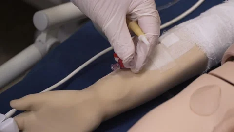 Close-up, a peripheral venous catheter is installed on simulation doll hand Stock Footage