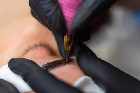 Close up of permanent eyebrow makeup procedure, beautician performing 스톡 사진