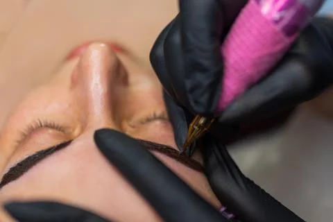 Close up of permanent eyebrow makeup procedure, beautician performing Fotos Stock