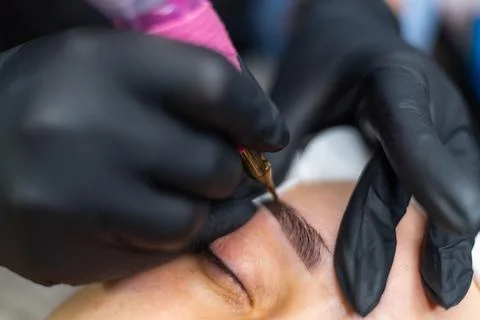 Close up of permanent eyebrow makeup procedure, beautician performing 스톡 사진