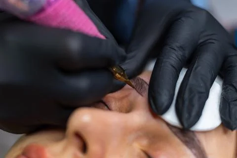 Close up of permanent eyebrow makeup procedure, beautician performing Stockfoto's