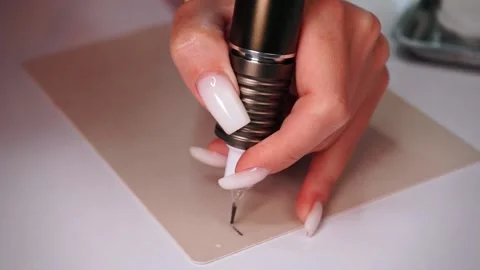 Close-up of a permanent makeup master's hand holding a permanent tattoo machine Stock Footage 188748930