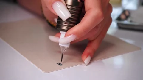 Close-up of a permanent makeup master's hand holding a permanent tattoo machine Stock Footage 188748968