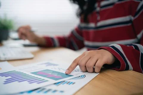 Close up of person analyzing financial chart report while sitting at wooden.. Stock Photos