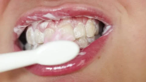 Close-up of person brushing teeth with pink and white toothpaste and toothbrush Stock Footage 340261311