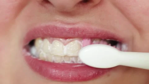 Close-up of person brushing teeth with pink bristles and white toothbrush Stock Footage 340261364