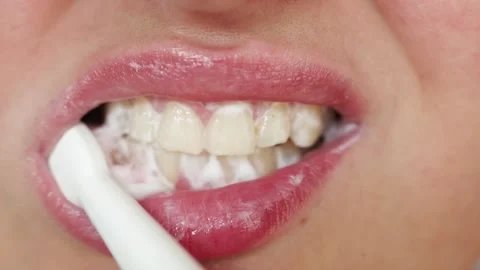 Close-up of a person brushing their teeth with a white electric toothbrush Stock Footage 340261344