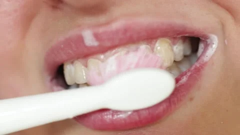 Close up of a person brushing their teeth with white toothpaste and a pink Stock Footage 340261355
