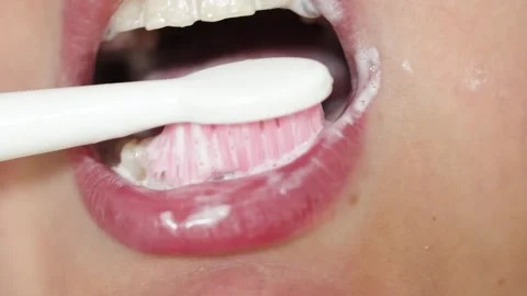 Close-up of a person brushing their teeth with a toothbrush and toothpaste Stock Footage 340261356