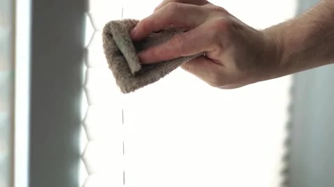 Close up of a person cleaning white window sunshade blinds on a bright sunn.. 動画素材 340159365