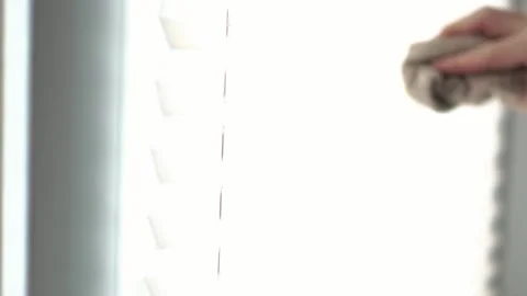 Close up of a person cleaning white window sunshade blinds on a bright sunn.. Stock Footage 340159381