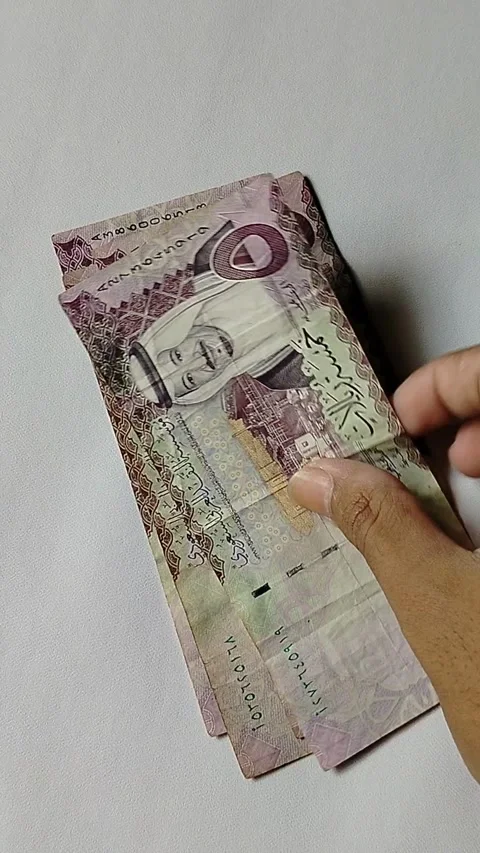 A close-up of a person counting 5 Saudi Riyal banknotes by hand, representing  Stock Footage 339795168