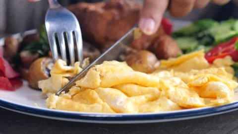 Close up of person cutting scrambled eggs with knife and fork on breakfast .. Stock-Footage 333032128