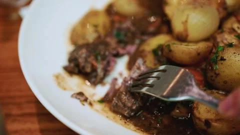 Close up of person cutting tender beef stew with potatoes and onions on whi.. Stock Footage 339758806