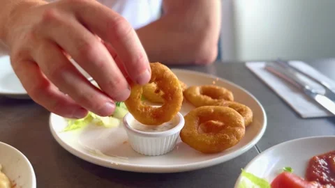 Close up of person dipping breaded calamari ring in dipping sauce at restaurant Stock Footage 339276143